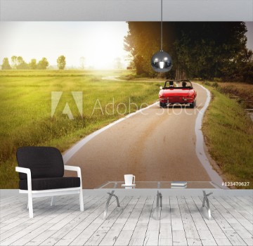 Picture of Classic red convertible car traveling in the countryside at sunset